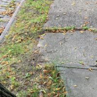 Cracked and uneven sidewalk that could lead to a tripping accident