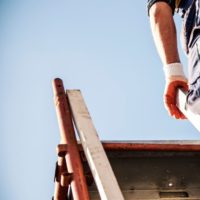 Worker climbing a ladder while working outside