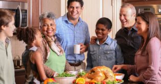 Diverse friends and family celebrating Thanksgiving together around an abundance of food.