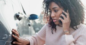 black woman looking at car after an accident