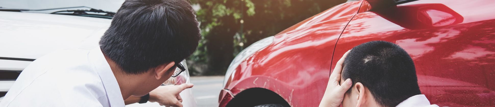 2 men accessing the damages to their vehicle after an accident.